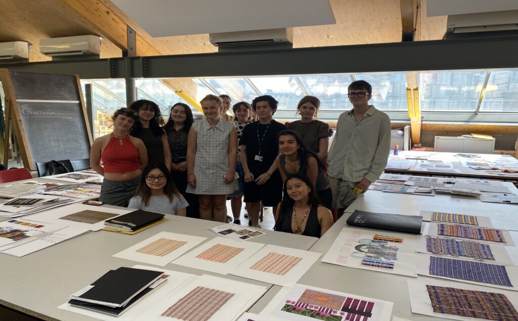 Students of Central Saint Martins London gather in the middle of a table surrounded by their moodboards.