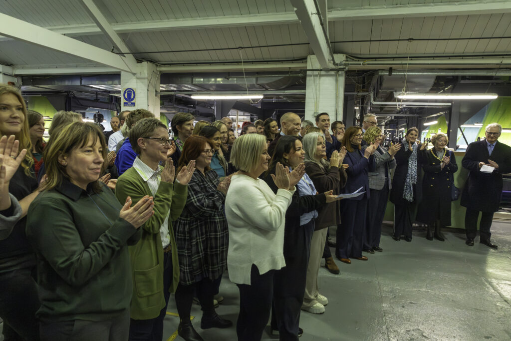 Colleagues clapping at the mill gathered around to watch presentation in weaving area