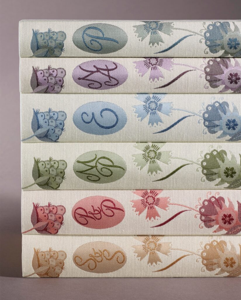 Collection of Jane Austen books covered in white fabric with coloured motifs