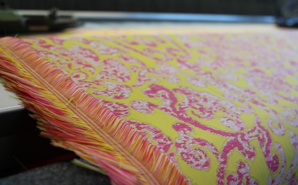 A bright yellow fabric with an azalea pink and white digitally distorted damask pattern.