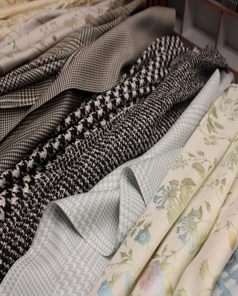 SS27 Apparel Fabrics laid next to each other including a pastel floral, a brown plain and a monochrome check.