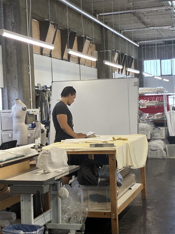 A man working with some fabric on a table at Maes London.